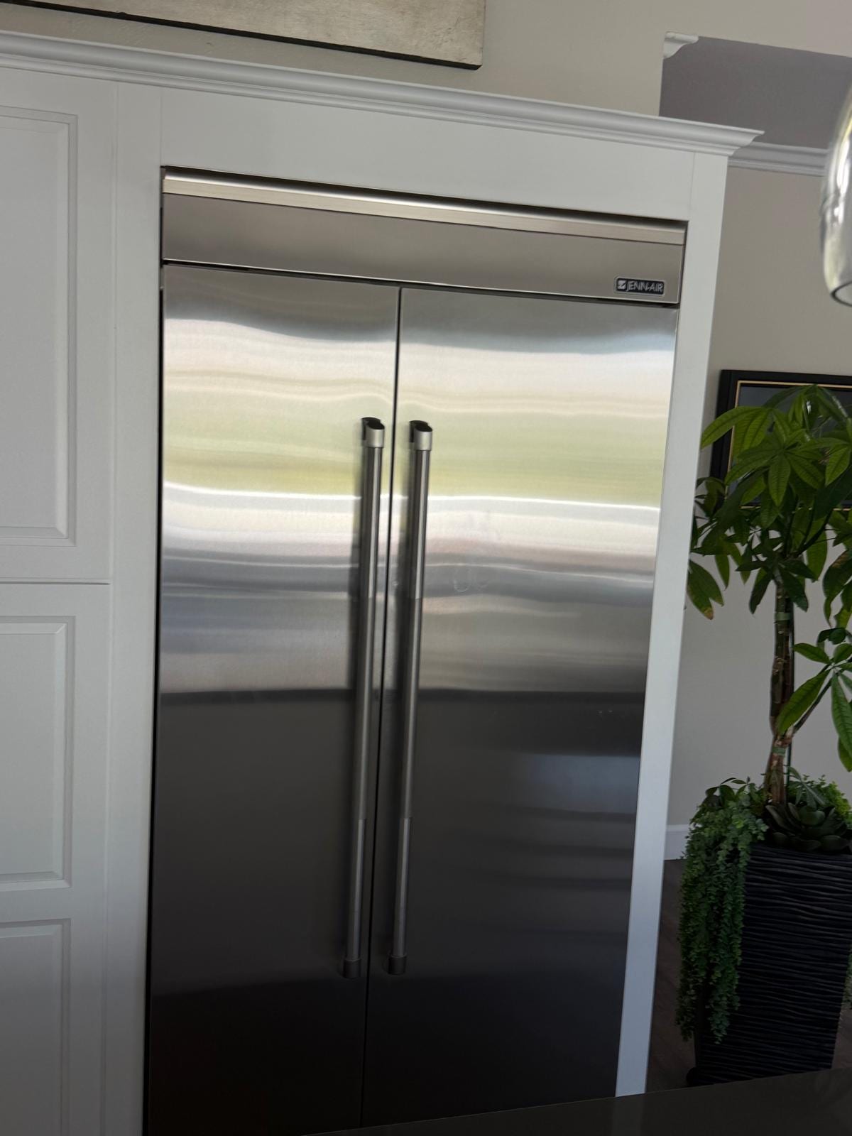 Stainless JennAir side-by-side refrigerator built into white kitchen cabinetry