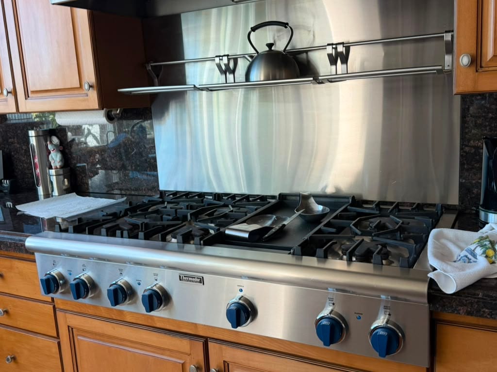 Stainless Thermador professional gas cooktop with blue control knobs set into a Newport Beach granite counter after a spark module and igniter replacement
