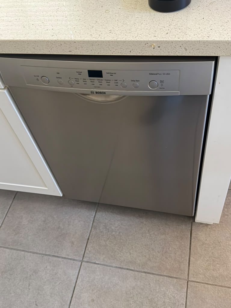 Stainless Bosch built-in dishwasher with a SilencePlus 50 dBA control panel, set under a quartz countertop on a tile floor in an Irvine kitchen after a spray arm replacement