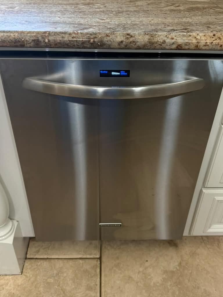 Stainless KitchenAid dishwasher with a lit display on its control panel, set under a countertop in a Santa Ana kitchen after a control board replacement