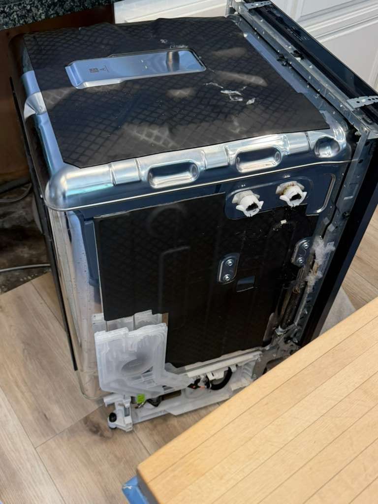 Underside of a Whirlpool dishwasher tilted out to expose the base, sump, and drain during a leak diagnosis in San Clemente