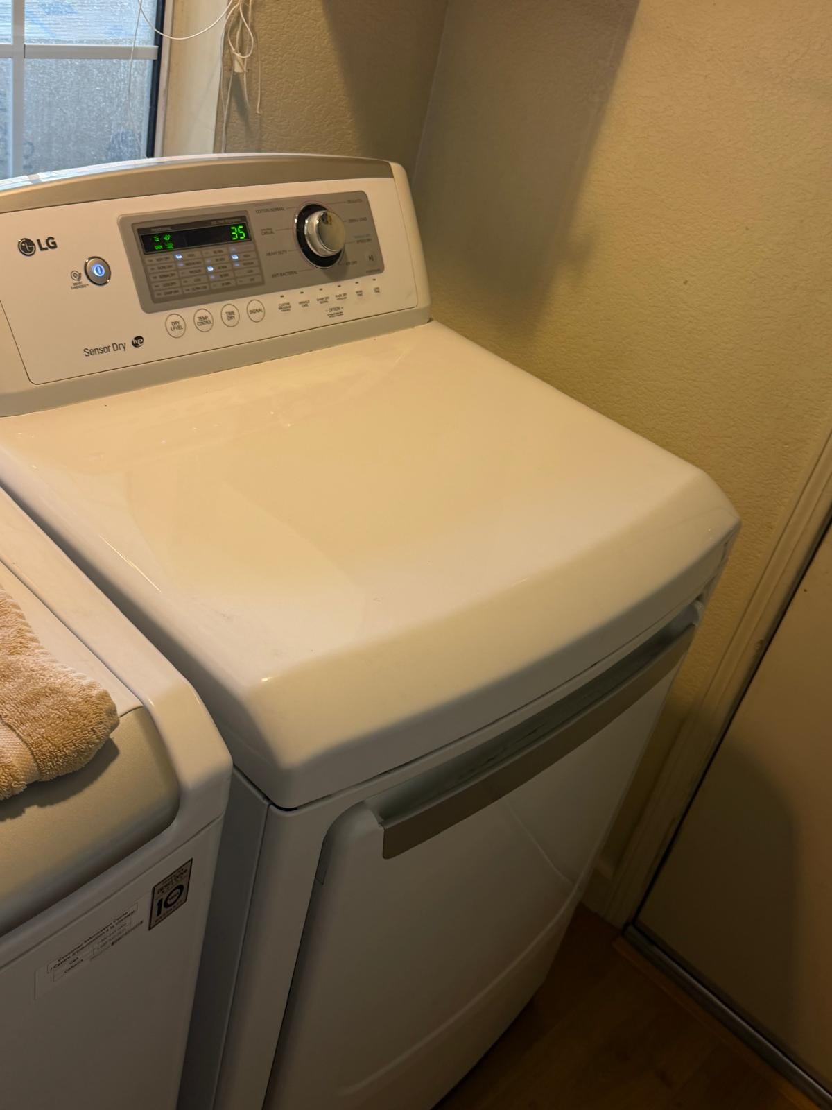 White LG dryer with its control display lit, standing beside a matching washer in a Chino laundry room
