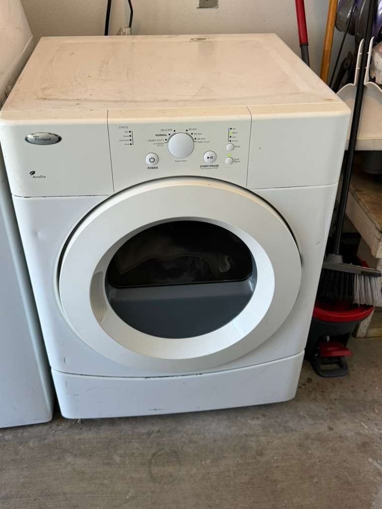 White Whirlpool AccuDry front-load dryer on a pedestal in a Long Beach garage, serviced for running cold with no heat