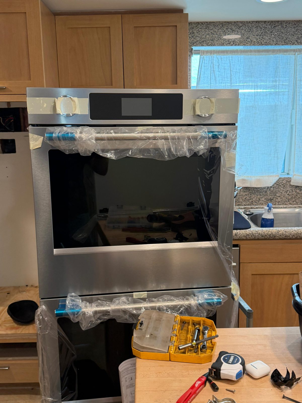 Newly installed KitchenAid double wall oven in a Newport Beach kitchen, factory plastic still in place during installation