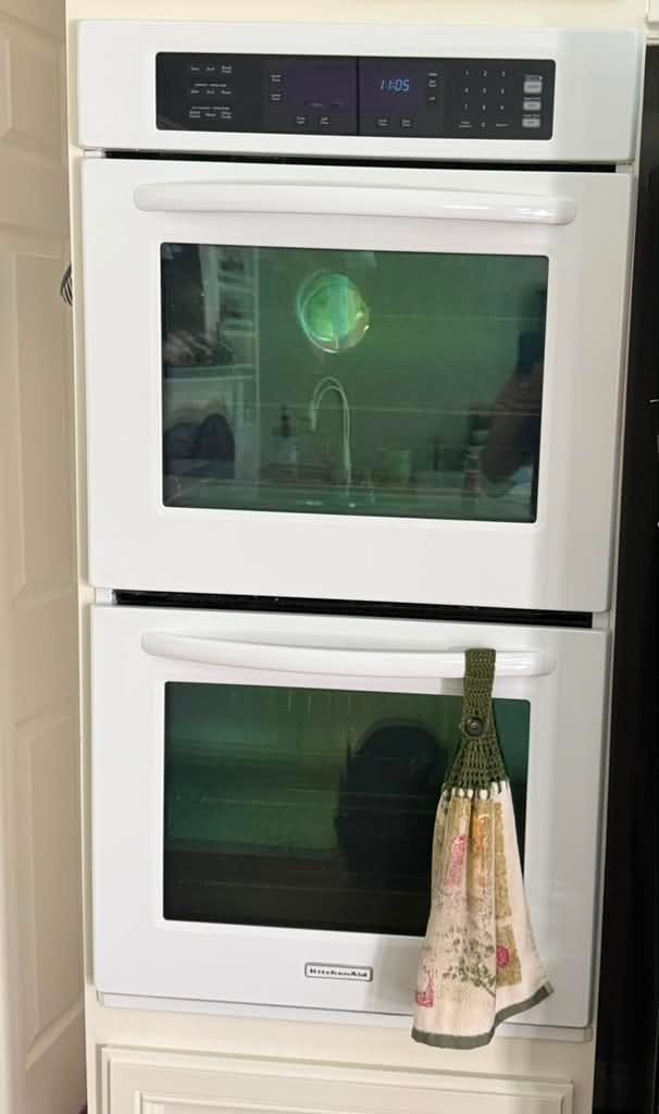 White KitchenAid built-in double wall oven set into cream cabinetry, with a lit digital control panel above the upper oven window and a lower oven below carrying the KitchenAid badge, in a Mission Viejo kitchen after an oven temperature sensor replacement