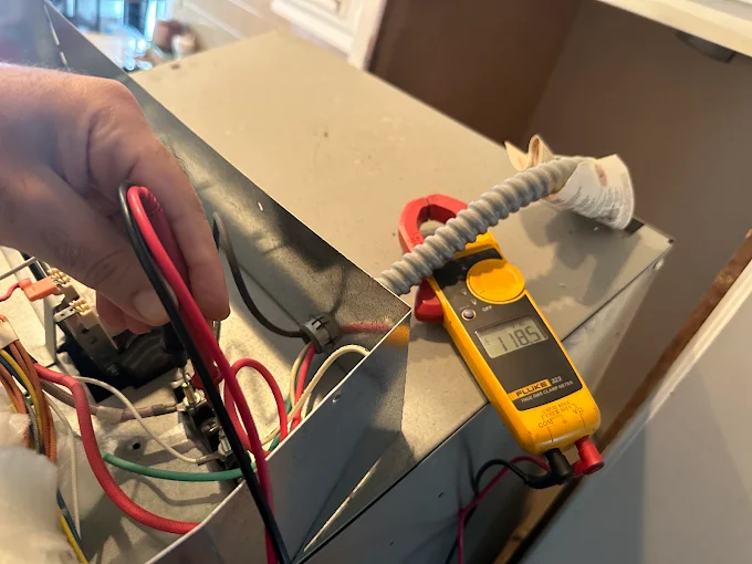 Technician using a Fluke clamp meter to test wiring during an appliance electrical diagnostic