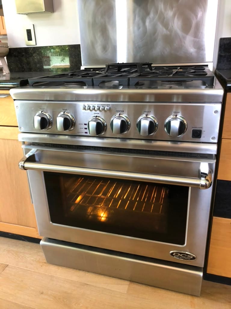 Stainless DCS professional gas range with the oven lit after a bake igniter repair in a Newport Beach kitchen
