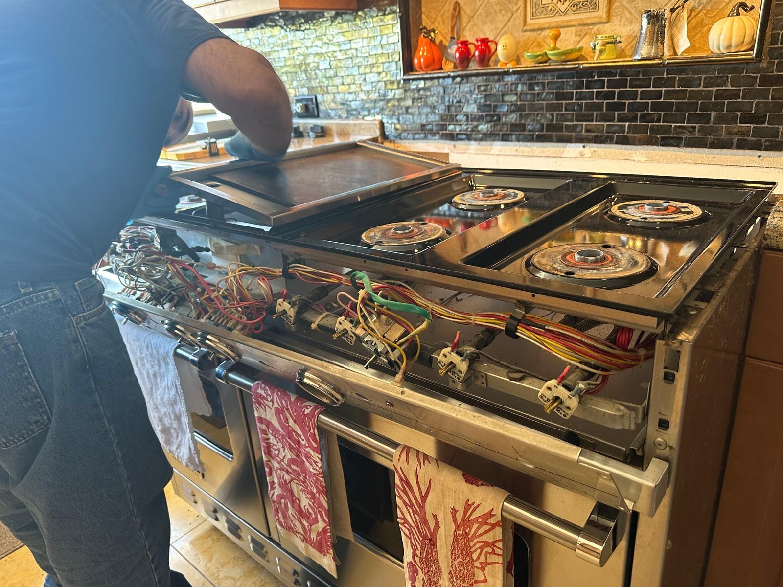 Thermador 48-inch professional gas range with the cooktop lifted, exposing the spark ignition module and igniter wiring harness in a San Clemente kitchen