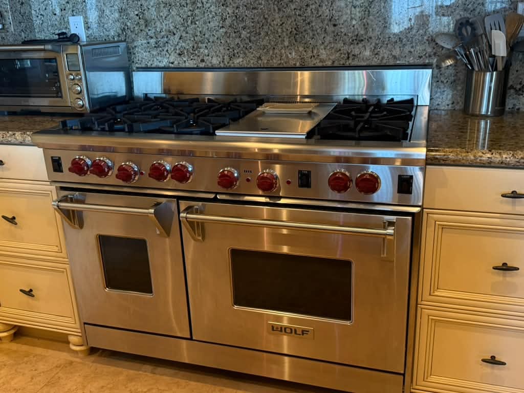 Stainless Wolf gas range with red knobs, six burners, a center griddle and two oven doors, Newport Beach