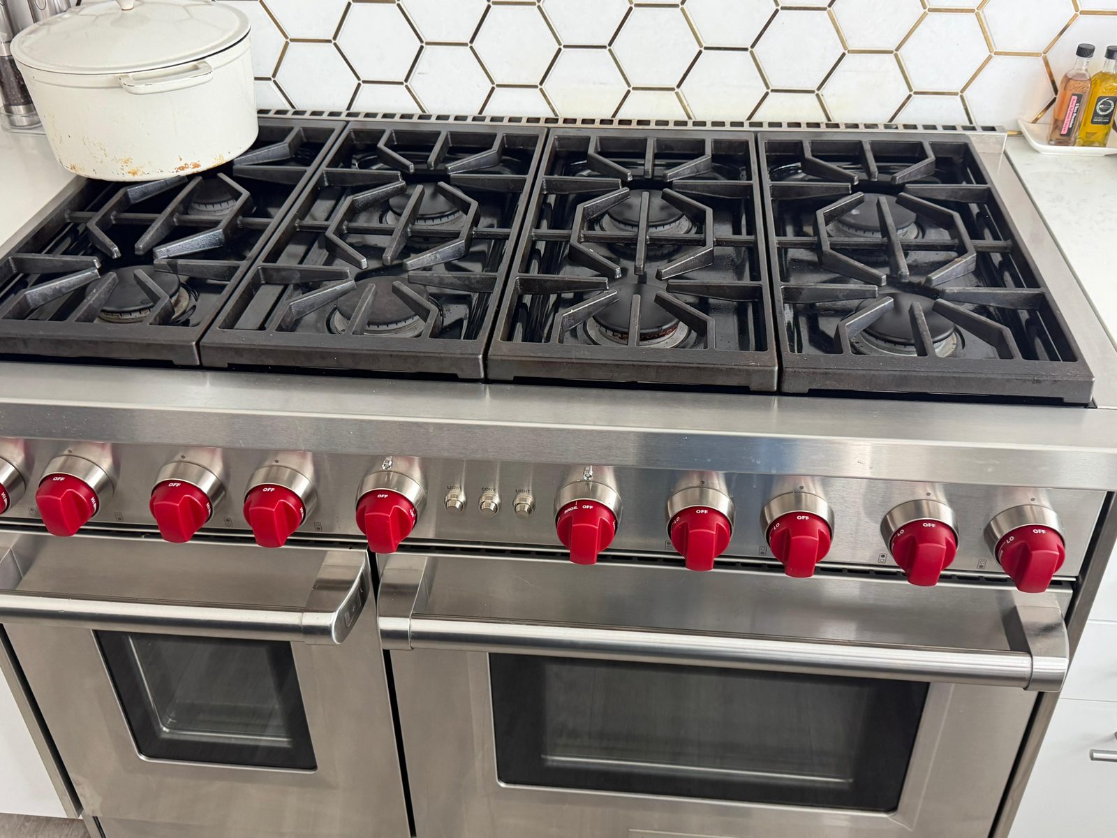 Wolf 6-burner professional gas range serviced in a Newport Beach kitchen with hex tile backsplash and signature red knobs