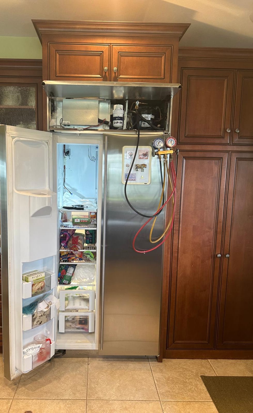GE Monogram refrigerator open with service gauges connected in a Laguna Beach kitchen