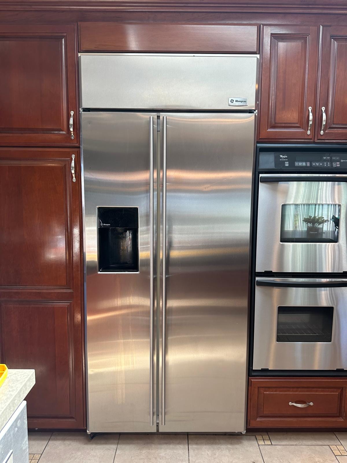 Stainless GE Monogram refrigerator with a front dispenser in a Huntington Beach kitchen
