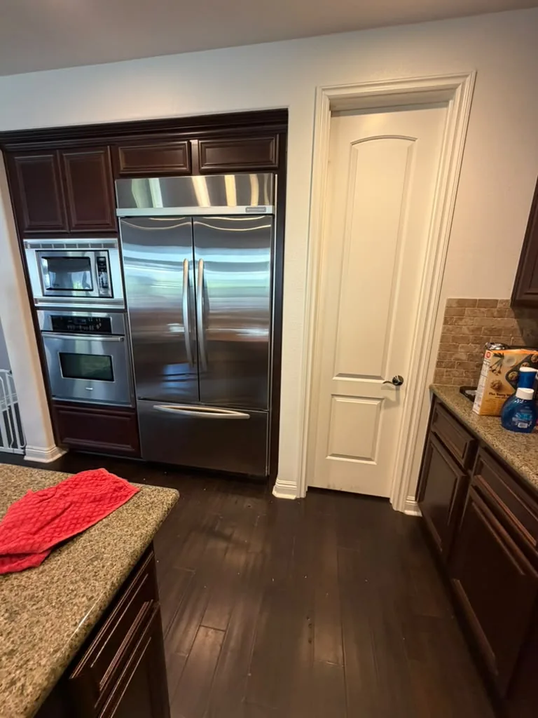 Stainless KitchenAid French-door refrigerator built into dark wood cabinetry beside a stainless wall oven in an Aliso Viejo kitchen