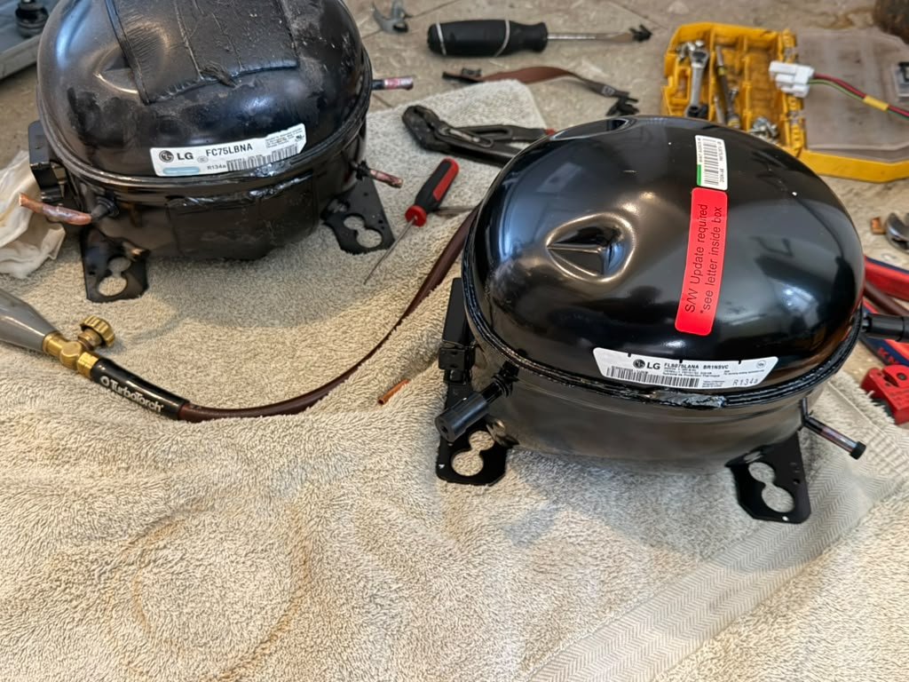 Side-by-side comparison on a workbench: the failed LG FC75LBNA compressor next to the new genuine FL80YLANA replacement, with a TurboTorch brazing kit visible, from an Orange, CA refrigerator repair