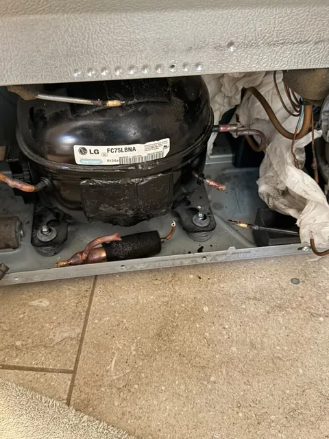 LG refrigerator with the lower access panel removed revealing the failed FC75LBNA linear compressor during an Orange, CA repair by Universal Appliances Repair