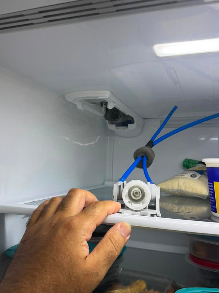 Close-up inside an LG refrigerator showing the water filter housing assembly with blue supply tubing connected, during a water filter and water filter housing replacement in Rancho Santa Margarita