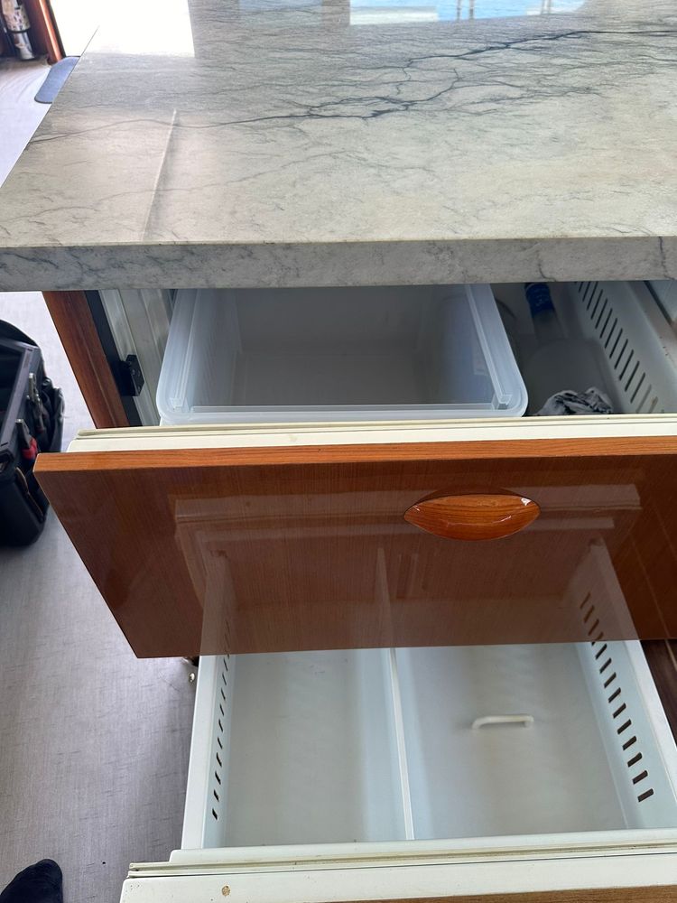 Open drawer-style marine refrigerator and freezer built into a boat's cabinetry, with both drawers pulled out