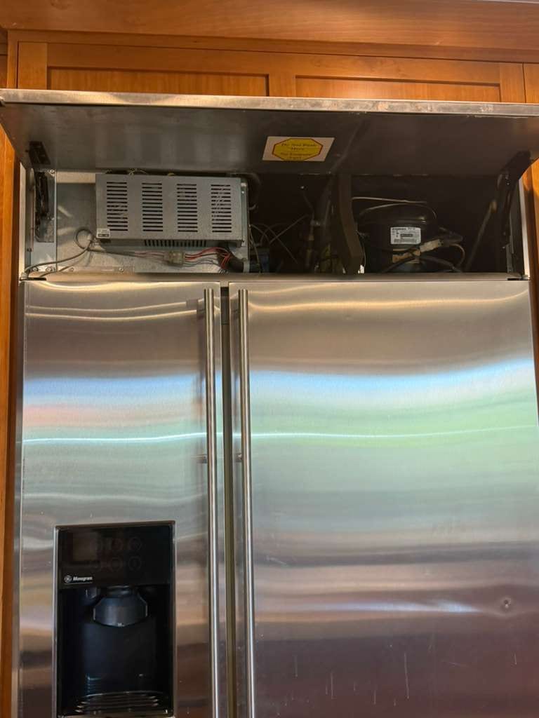 Monogram built-in refrigerator with its upper service compartment open during control-board and inverter-board replacement in Anaheim