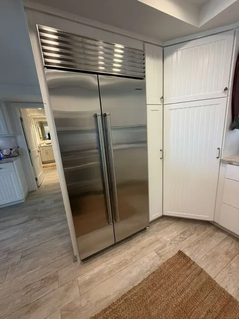Stainless built-in Sub-Zero refrigerator in a white-cabinet kitchen