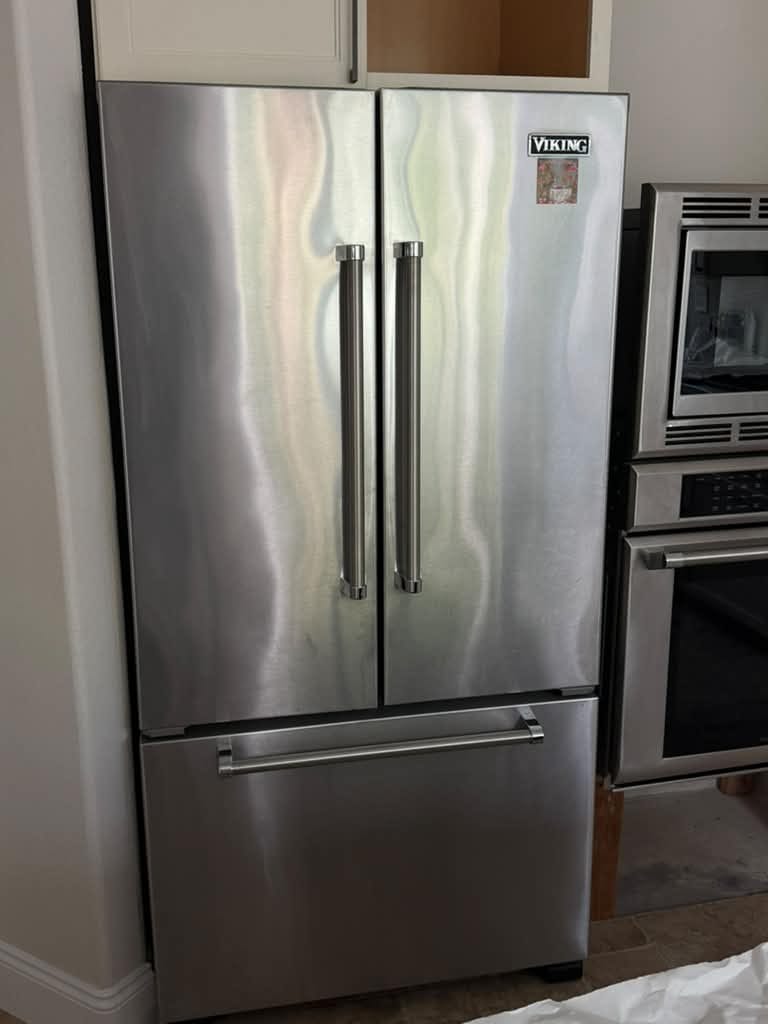 Stainless Viking French-door refrigerator with a bottom freezer beside built-in ovens