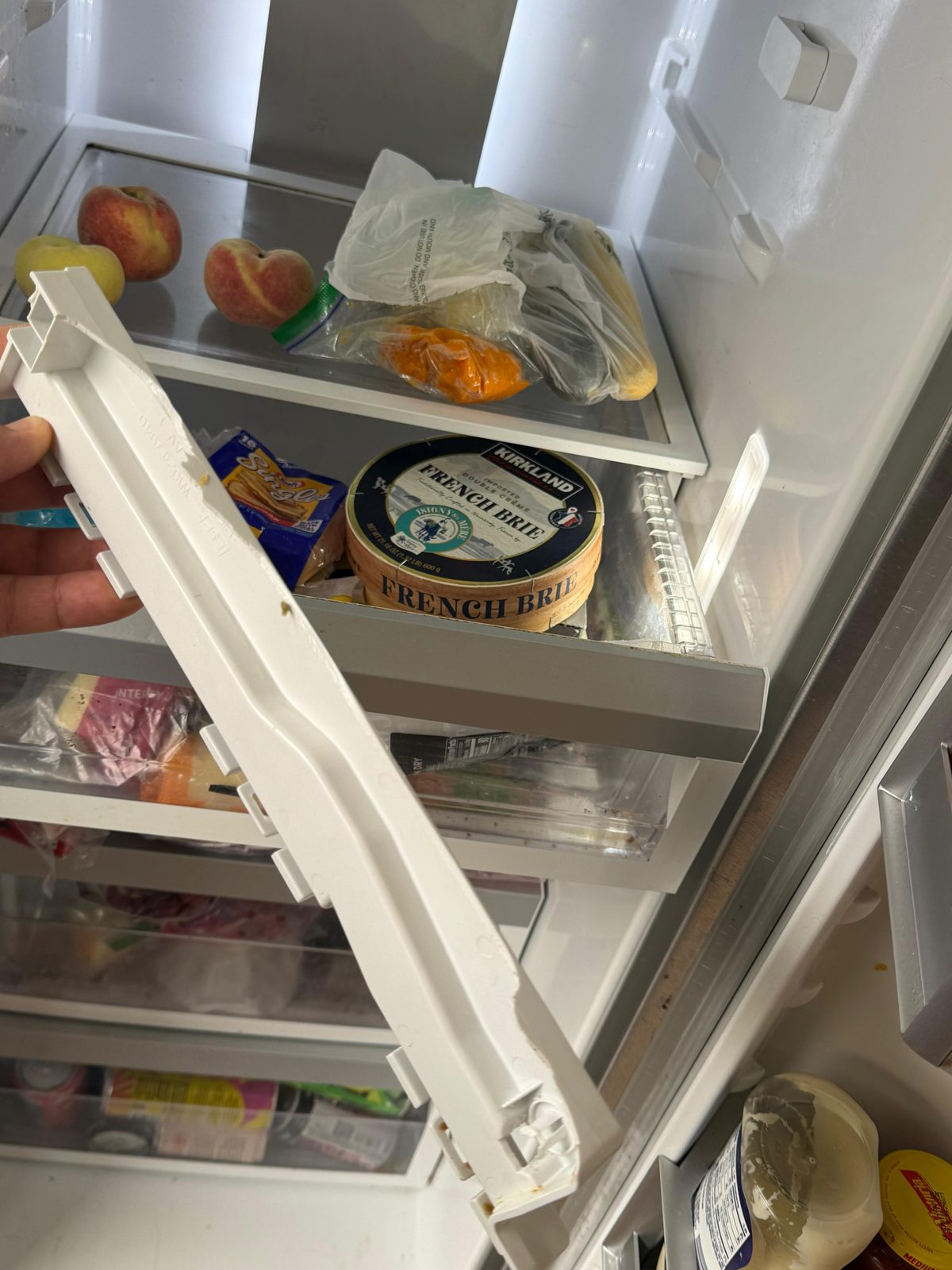 Technician holding the replacement drawer rail bracket from a Whirlpool refrigerator during a Laguna Beach service call
