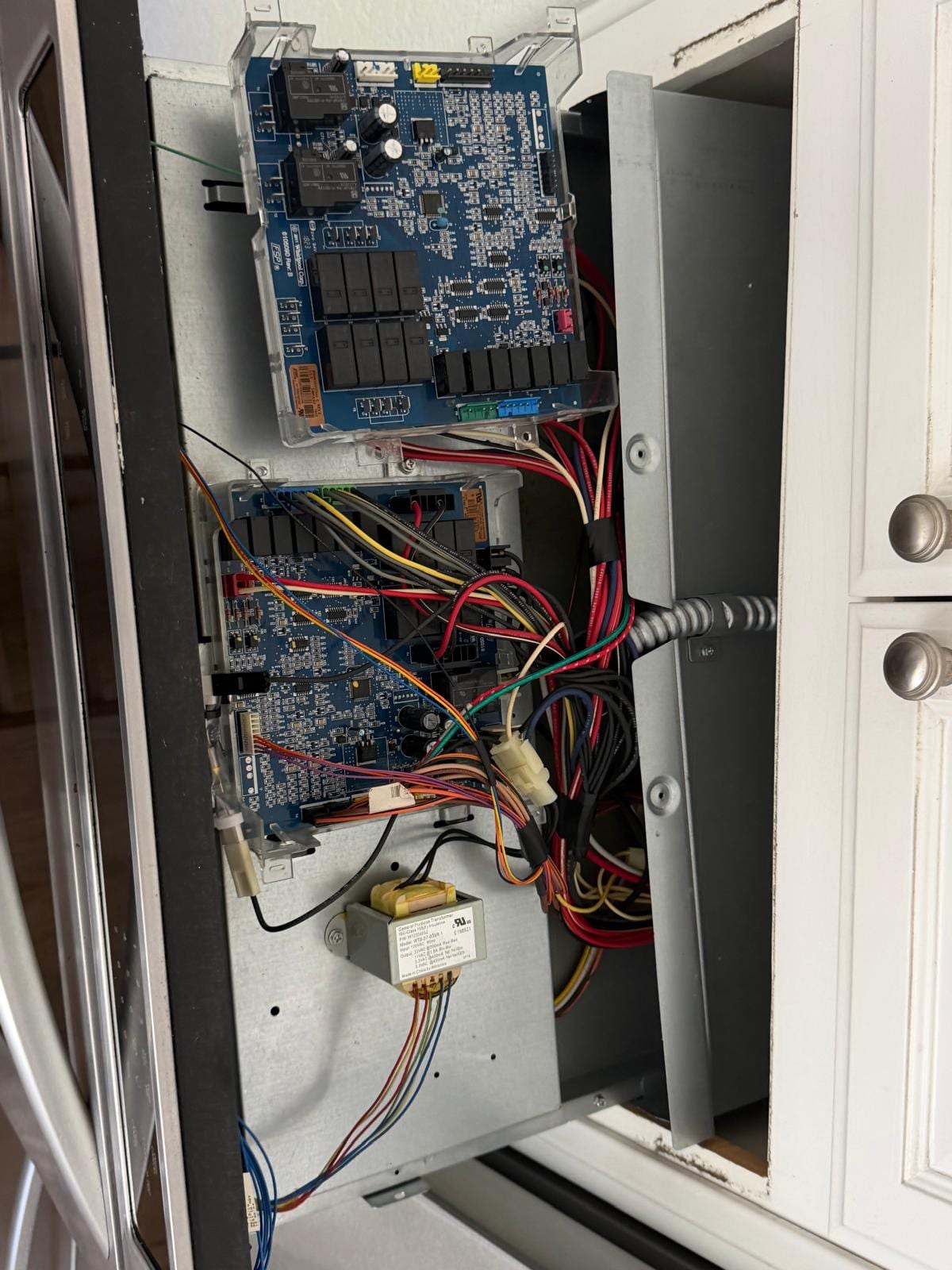 Close-up of two control boards, wiring and a transformer inside the opened control panel of a KitchenAid double wall oven in San Clemente
