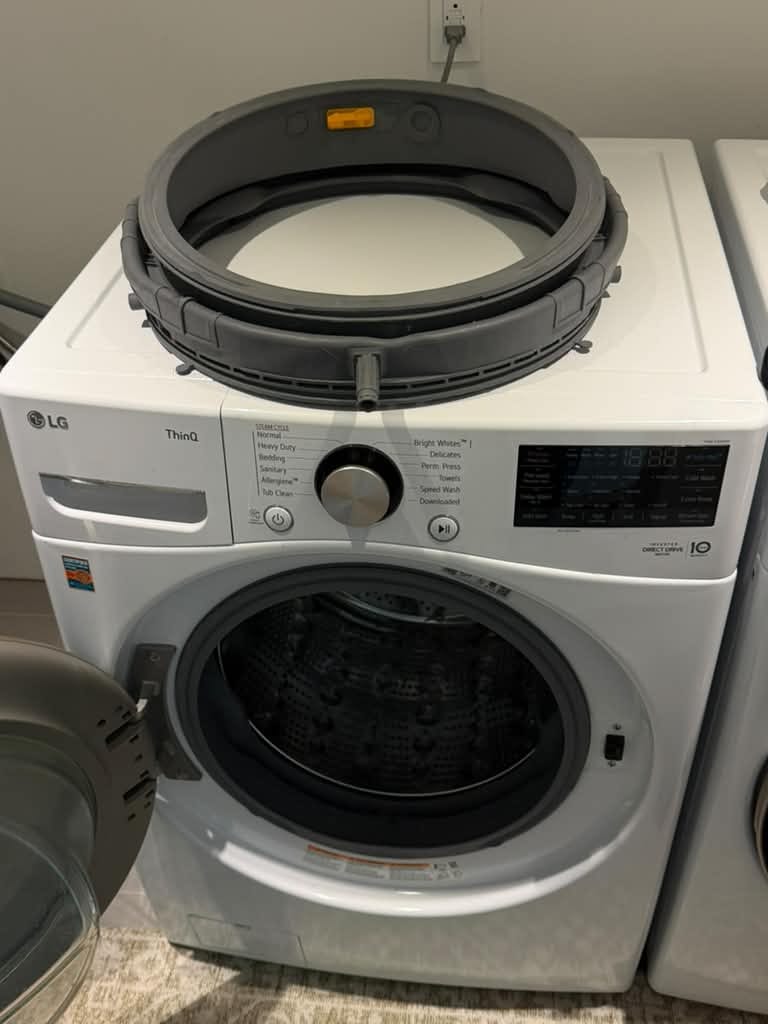 LG front-load washer in Beverly Hills with a door gasket resting on top and a gasket fitted in the door opening, during a door gasket replacement