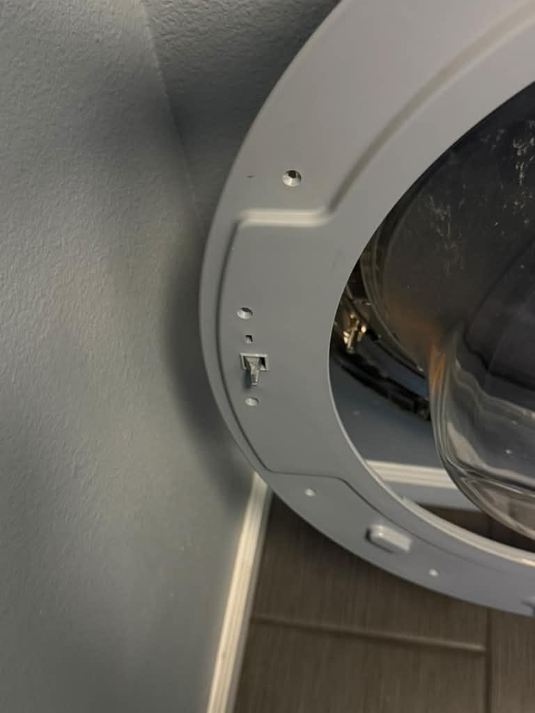 Open grey door of an LG front-load washer in Cypress, showing the door hook on the door frame after the door hook and door lock were replaced