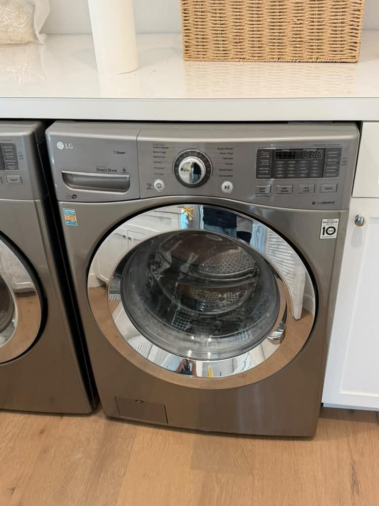 Silver LG front-load washer under a white counter in a Newport Beach laundry area