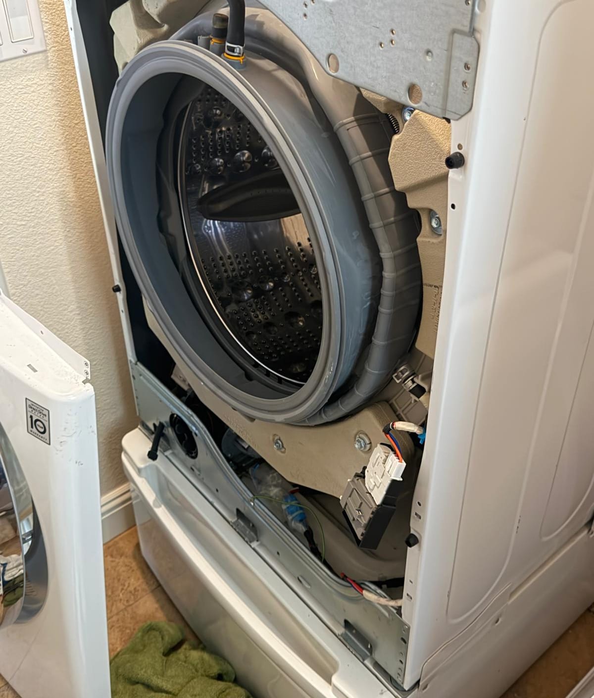 White LG front-load washer with the front panel removed during service