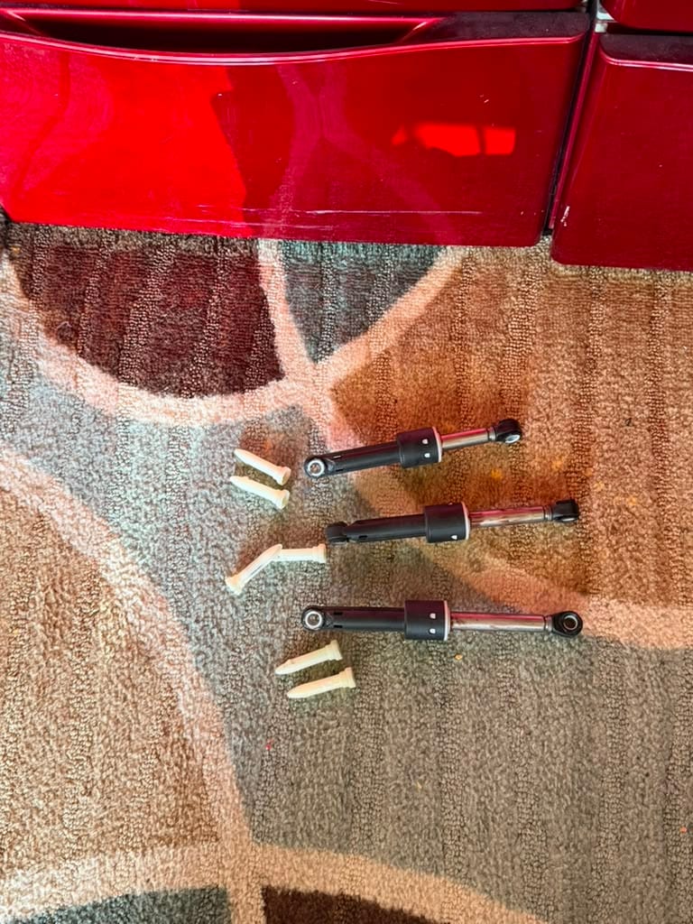 Three worn LG washer shock absorbers and their plastic retaining clips removed during a repair in Fountain Valley, CA