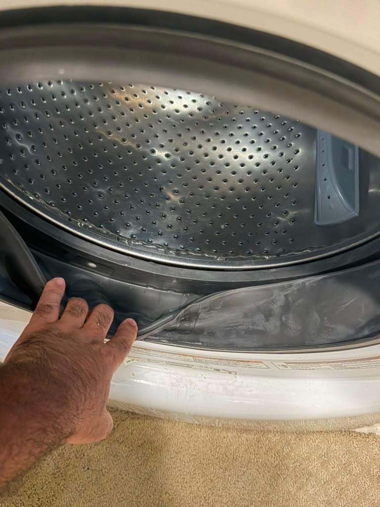Technician seating a new rubber door boot gasket around the drum opening of a Whirlpool front-load washer to stop a door leak