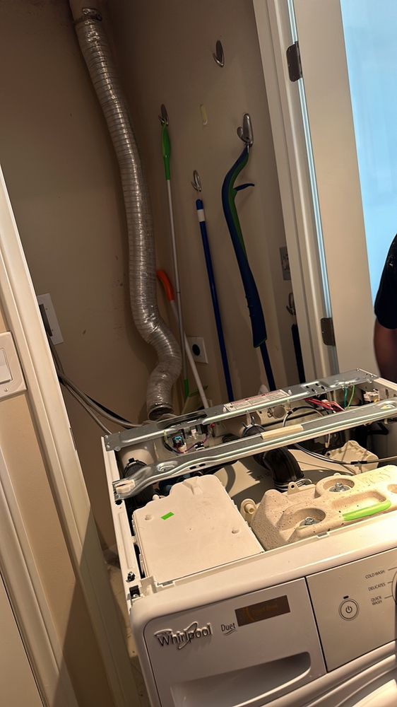 Whirlpool Duet washer with the top panel removed, exposing the control board and wiring harness, in a laundry closet