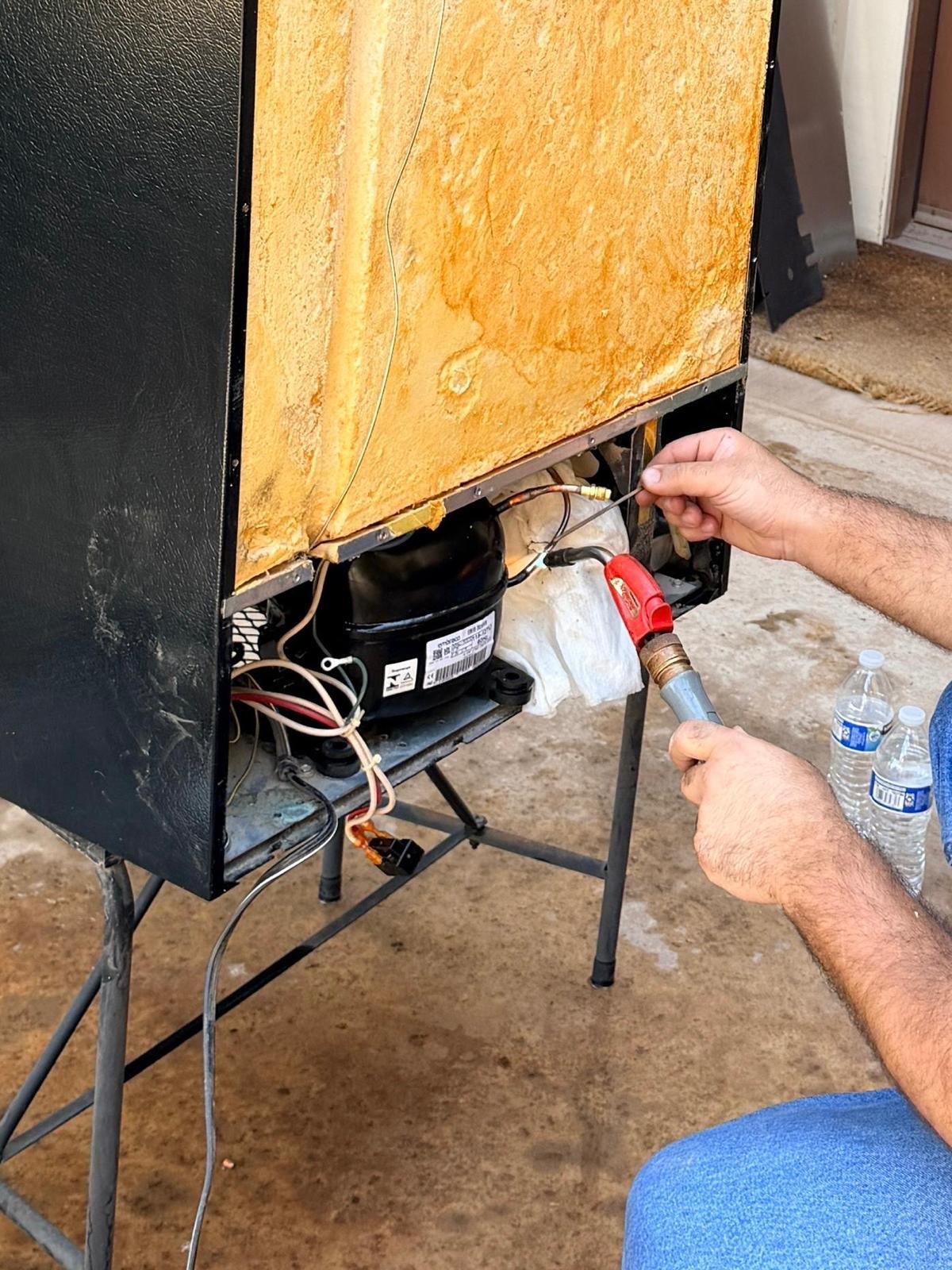 Universal Appliances Repair technician brazing a new compressor onto a Viking wine cooler during a Costa Mesa service call