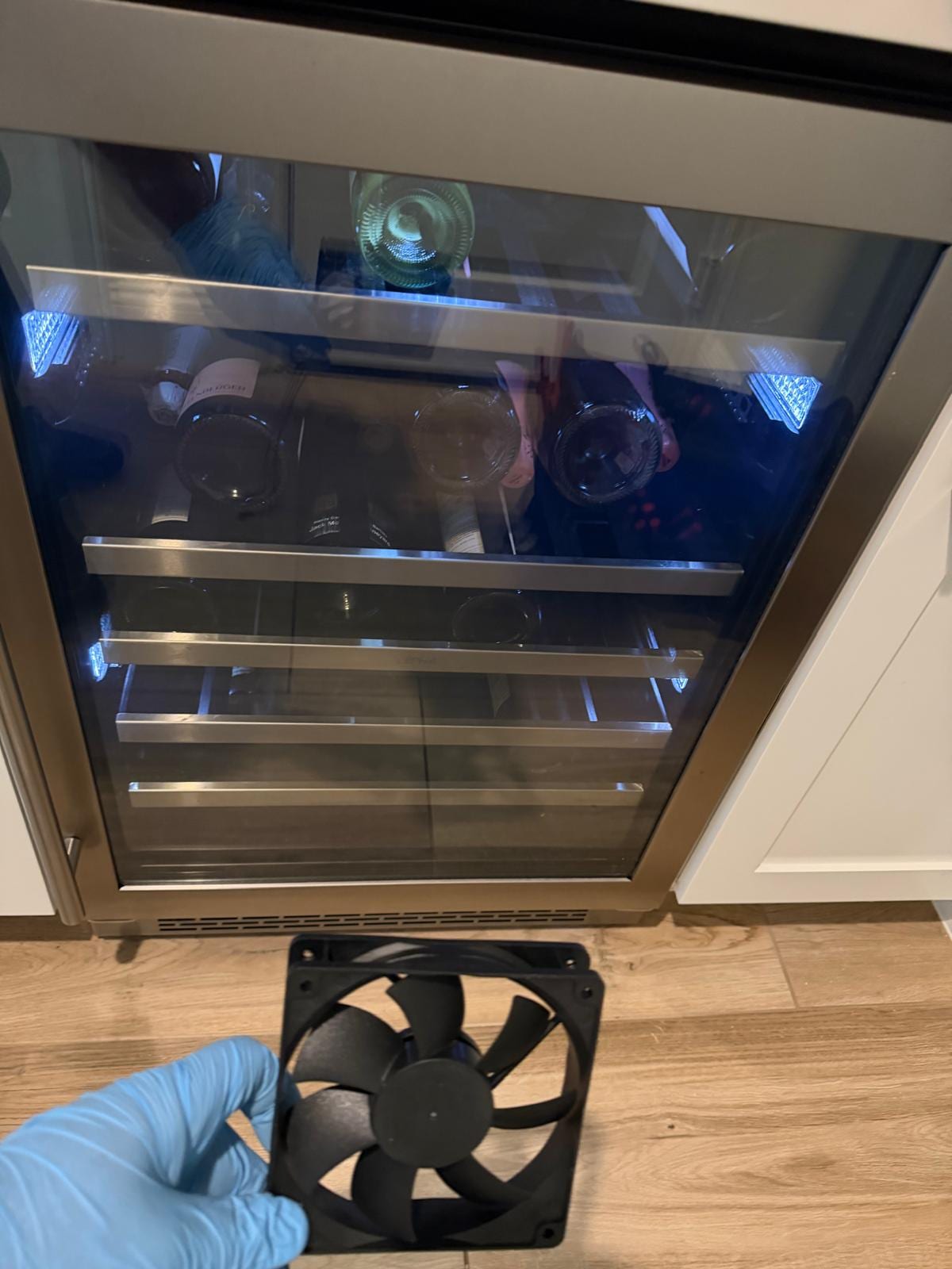 Zephyr built-in wine cooler with a glass door in Ladera Ranch, with a cooling fan held up in front of it during a fan replacement