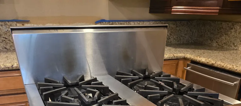 Photo from Rachel Padilla's review showing the stainless pro-style gas range we serviced, its backguard raised above the star-shaped cast-iron burner grates