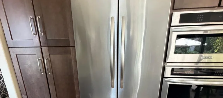 Photo from Eleonora Abukova's review showing the stainless steel side-by-side refrigerator we serviced, beside the KitchenAid wall oven