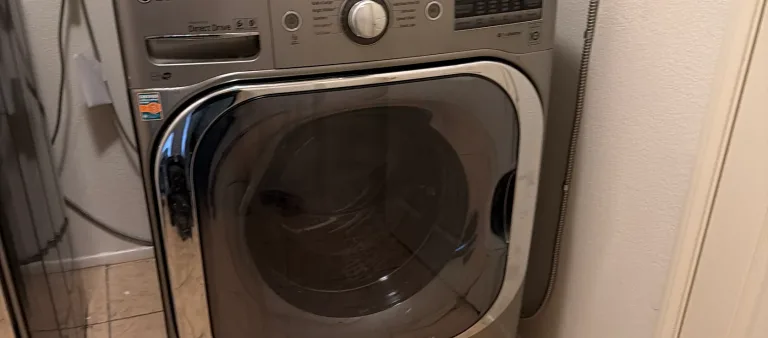 Photo from Ahmed El Korashy's review showing the stainless LG front-load washer we repaired, with its fill hose running down the side of the cabinet